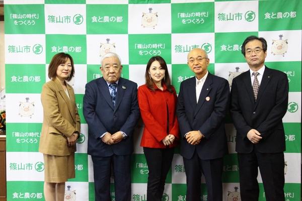 スーツを着た男女と市長が中央にいる山口 かおるさんと並んでいる写真
